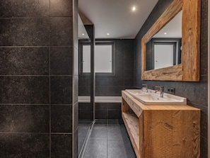 A modern bathroom with dark tiles, a wooden vanity, and a large mirror. - Luxury Duplex Apartment in Central Val-d'Isère, Near Slopes, with Large South-Facing Terrace (Val-d'Isère)