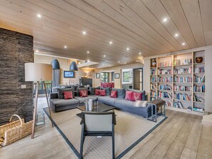 Ein modernes Wohnzimmer mit einem Ecksofa, einem Glastisch und einem Bücherregal voller Bücher.