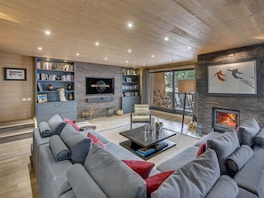 A modern living room with a large flat-screen TV, a fireplace, and a cozy seating area. - Luxury Duplex Apartment in Central Val-d'Isère, Near Slopes, with Large South-Facing Terrace (Val-d'Isère)