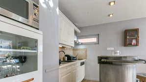Una cocina moderna con armarios blancos, horno empotrado, cafetera y ventana sobre el fregadero.