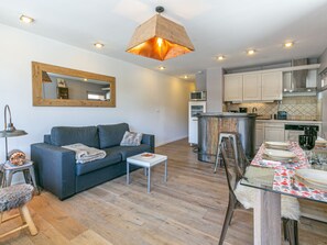 A modern living room with a sofa, coffee table, and a dining area with a table set for two. - Cozy Apartment with Wi-Fi, Central Location, Near Ski Slopes in Val-d'Isère (Val-d'Isère)