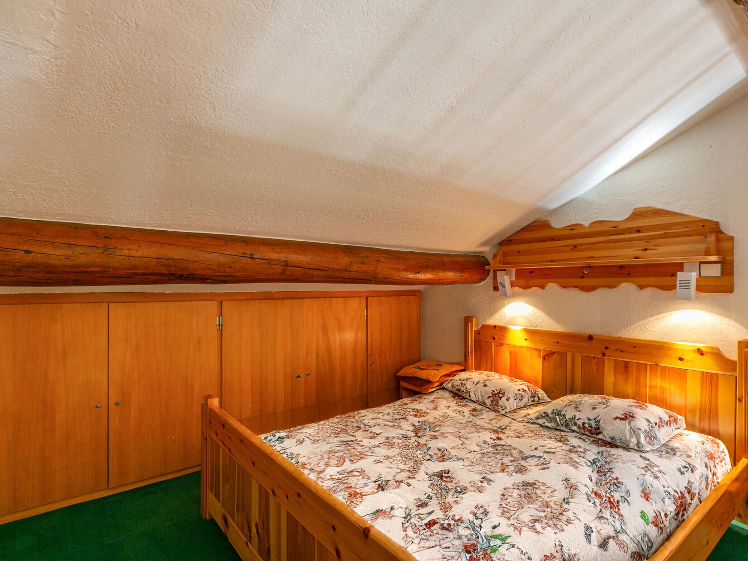 Una habitación de madera con una cama, un armario y una viga de techo de madera.