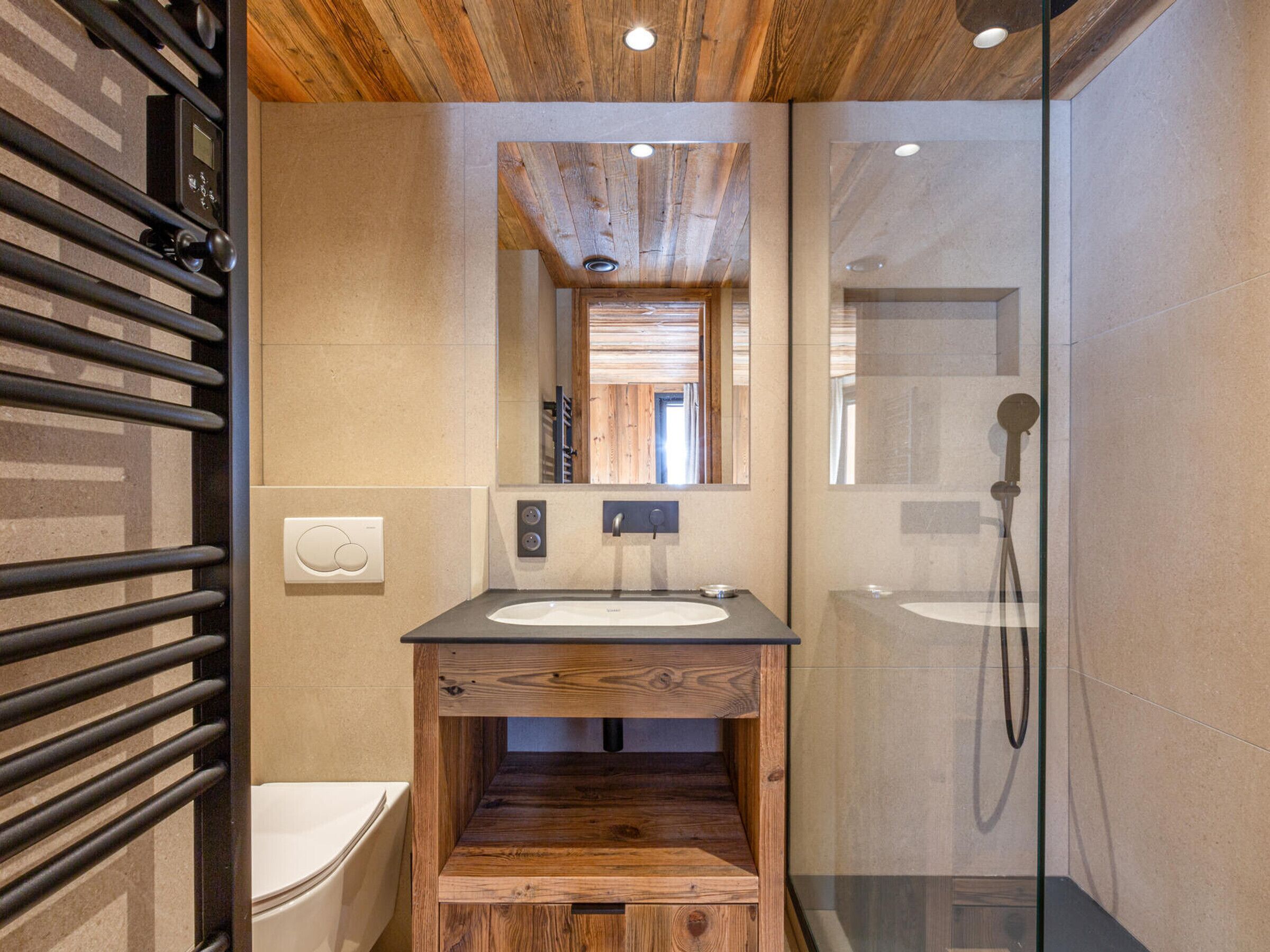 Ein modernes Badezimmer mit einem Holzkosmetikschrank, einer Glasdusche und einer Badewanne.