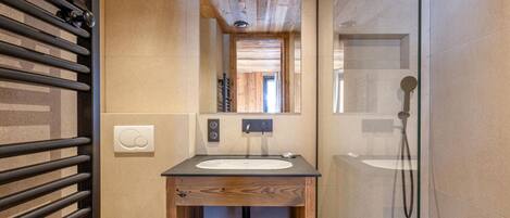 Ein modernes Badezimmer mit einem Holzkosmetikschrank, einer Glasdusche und einer Badewanne.