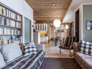 A cozy living room with a sofa, armchairs, and a bookshelf filled with books.