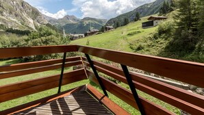 A wooden deck with a view of a mountainous landscape, including houses and a power line.