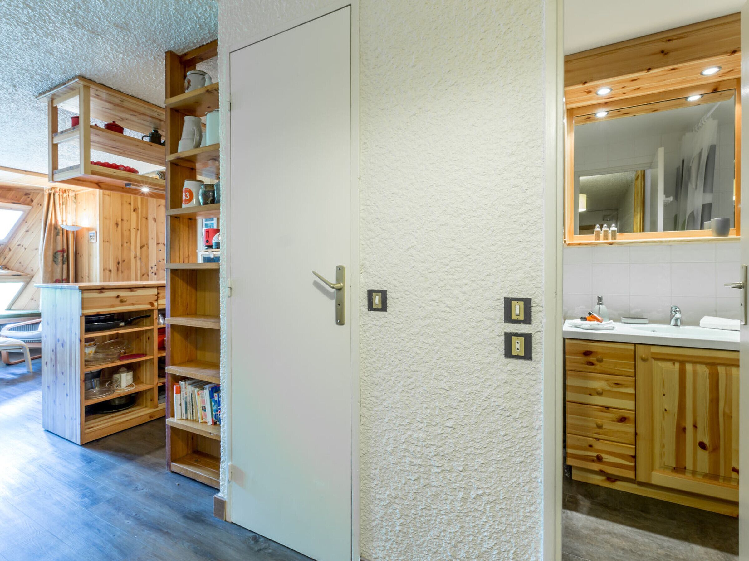 A modern bathroom with wooden cabinets, a white sink, and a large mirror.