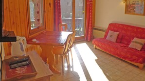 A wooden interior with a dining table, chairs, a sofa, and a window with curtains. - T2 apartment with mezzanine in village center, pets allowed (Samoëns)