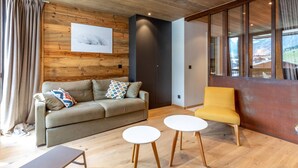 A modern living room with a wooden ceiling, a sofa, a yellow armchair, and two small white tables. - Stunning 2-Bedroom Condo with Wi-Fi, 2 Baths & Mountain Views in Central Val-d'Isère (Val-d'Isère)
