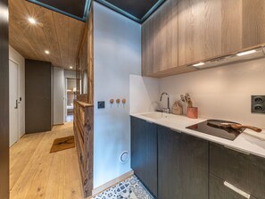 A modern kitchen with wooden cabinets, a white countertop, and a built-in stove.
