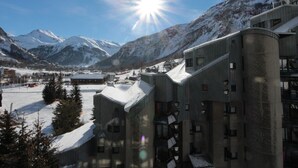 Une station de montagne enneigée, avec un bâtiment imposant doté de nombreuses fenêtres et d’un toit en pente.