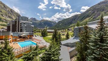 A hotel with a pool, surrounded by mountains and trees.