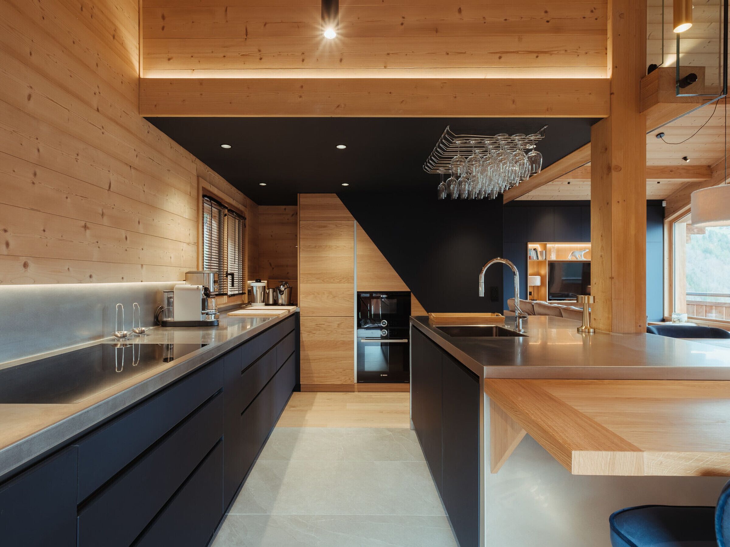 A modern kitchen with wooden walls, a central island, and a built-in dishwasher.