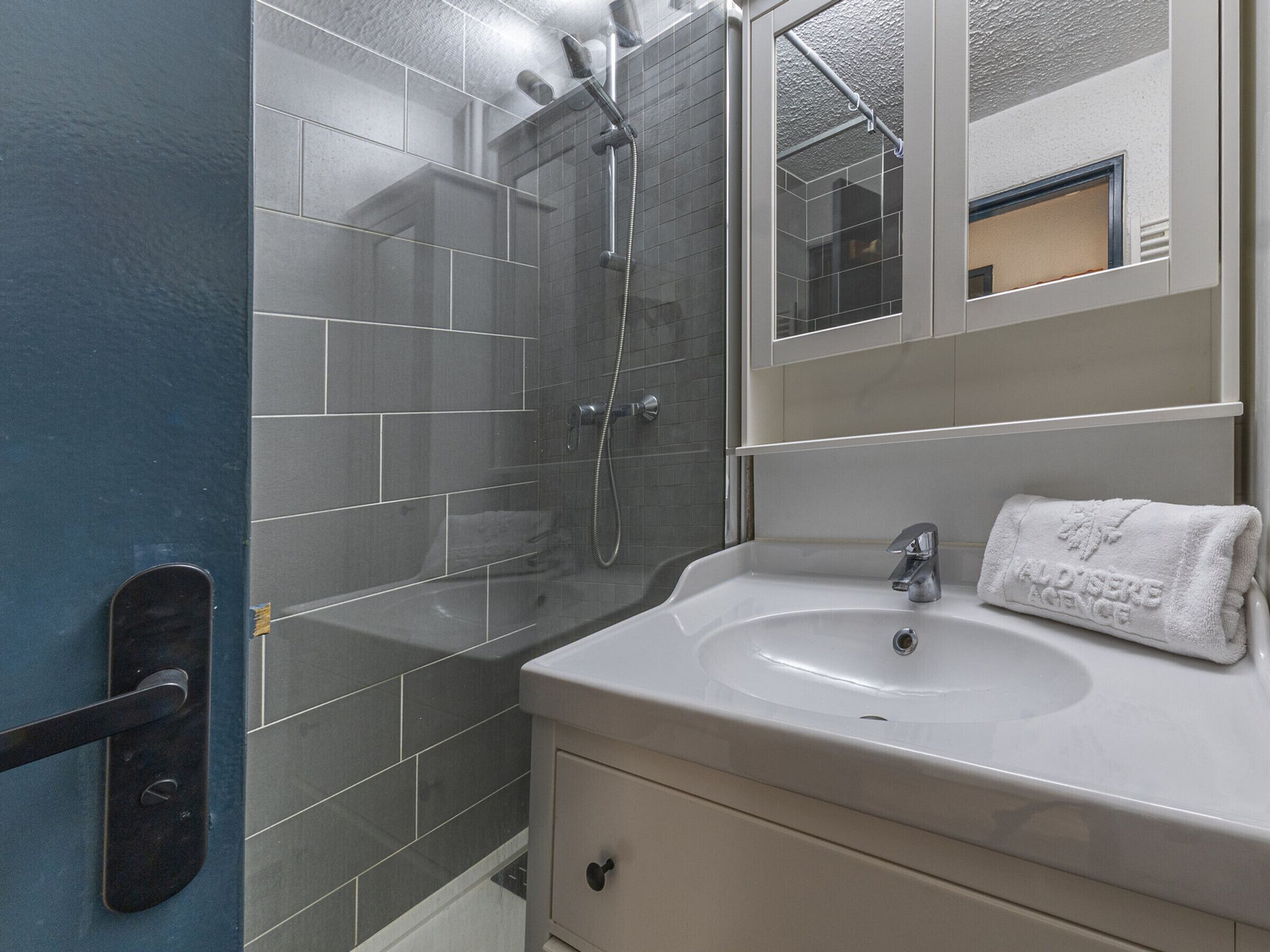 A bathroom with a shower, a sink, and a mirror.