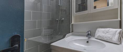 A bathroom with a shower, a sink, and a mirror.