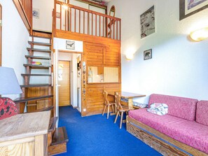 Een gezellige kamer met een stapelbed, een houten trap, een klein tafeltje en een roze bank.