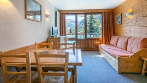 Une pièce chaleureuse avec une table en bois, des chaises, un canapé et un téléviseur.