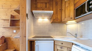 Une cuisine de taille réduite, dotée de meubles en bois, d’un four à micro-ondes encastré, d’un lave-vaisselle et d’un évier.