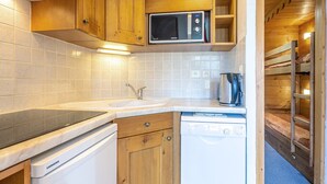 Une cuisine de taille réduite, dotée de meubles en bois, d’un four à micro-ondes, d’un évier et d’un lave-vaisselle.