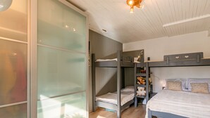 Ein Schlafzimmer mit Etagenbetten, einem Nachttisch und einem Kleiderschrank mit Schiebetüren.