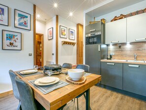 Eine moderne Küche mit Edelstahlgeräten, einem Holzespeisetisch gedeckt mit Tellern und Gläsern sowie gerahmten Bildern an der Wand.