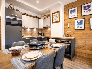 A modern kitchen with a dining area, wooden paneling, and framed artwork on the wall.