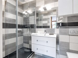 A modern bathroom with a glass-enclosed shower, a white vanity with a mirror, and a toilet.