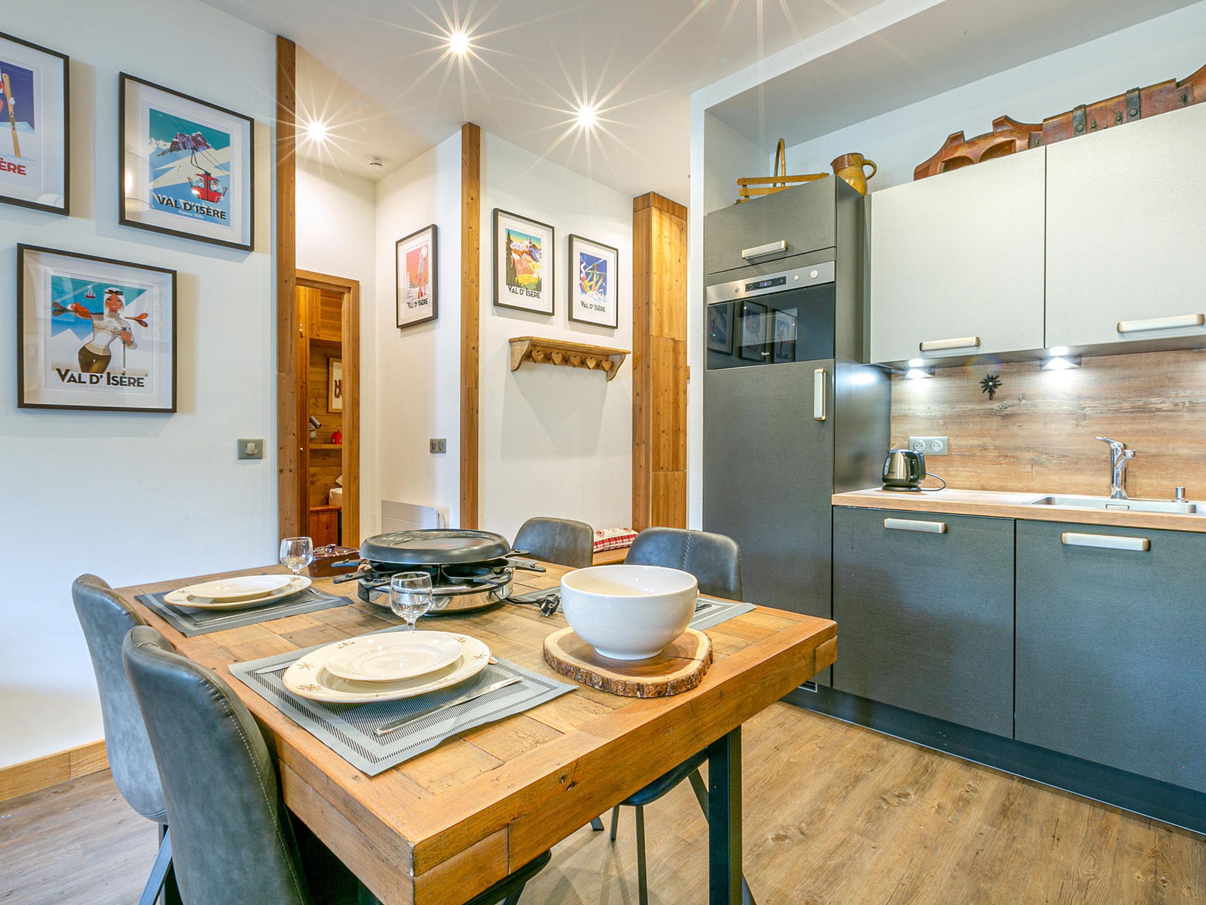 Eine moderne Küche mit Edelstahlgeräten, einem Holzespeisetisch gedeckt mit Tellern und Gläsern sowie gerahmten Bildern an der Wand.