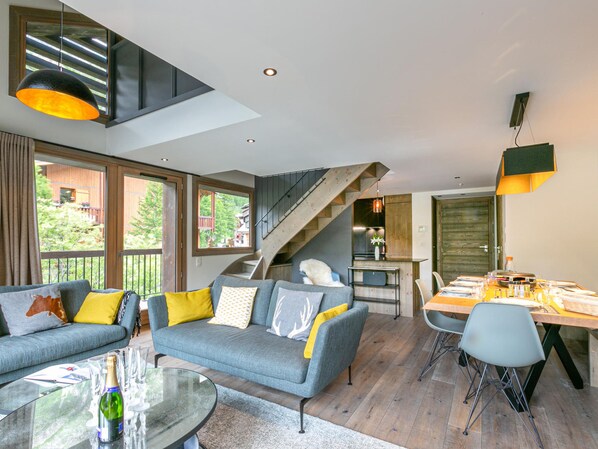 A modern living space with a sofa, dining table, and a staircase.