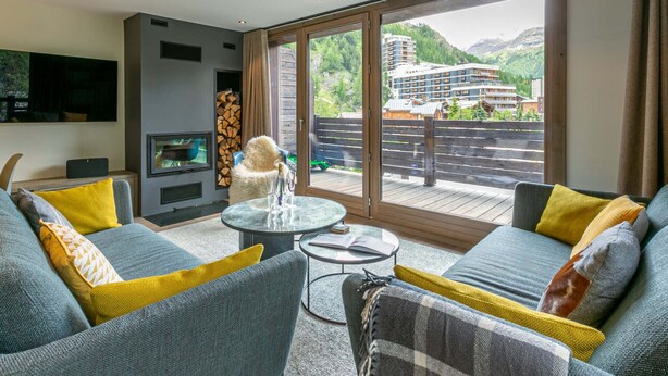 A modern living room with a sofa set, a glass coffee table, and a fireplace. - Elegant Duplex Apartment with Great Light, WiFi, and Parking in Val-d'Isère (Val-d'Isère)