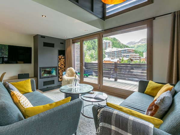 A modern living room with a sofa set, a glass coffee table, and a fireplace.
