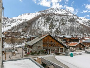 Un pueblo de montaña con edificios de madera y un edificio de piedra con un letrero que dice 'GARAGE'.