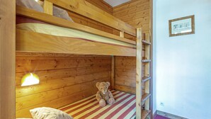 Een stapelbed met een teddybeer op het onderbed, een kussen en een klein plankje.
