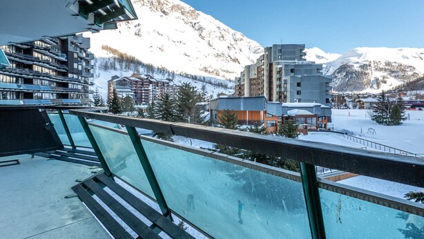 Un balcone con vista su una montagna innevata e degli edifici.