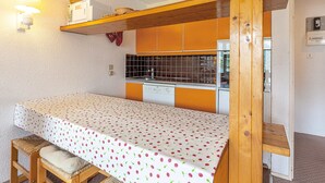 Una stanza piccola e accogliente con angolo cottura, un letto con copriletto decorato e una panca in legno con cuscini.
