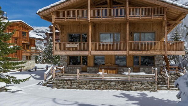 Een houten chalet met een stenen fundering, meerdere balkons en een bordje met de tekst 'LE MISTRALE'.