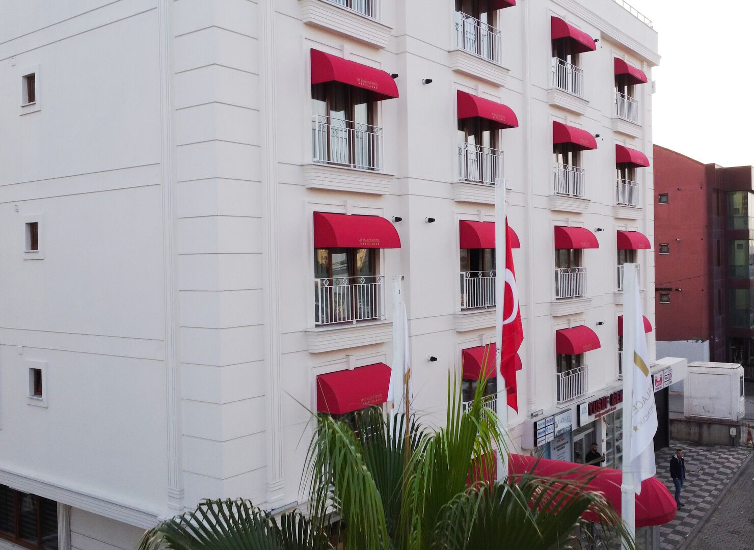 Un hotel a più piani con balconi e tende da sole rosse.