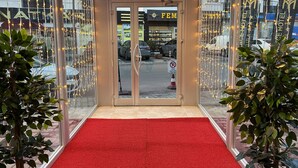 A hotel entrance with a red carpet, glass doors, and string lights. - MY PALACE TUZLA (Tuzla)