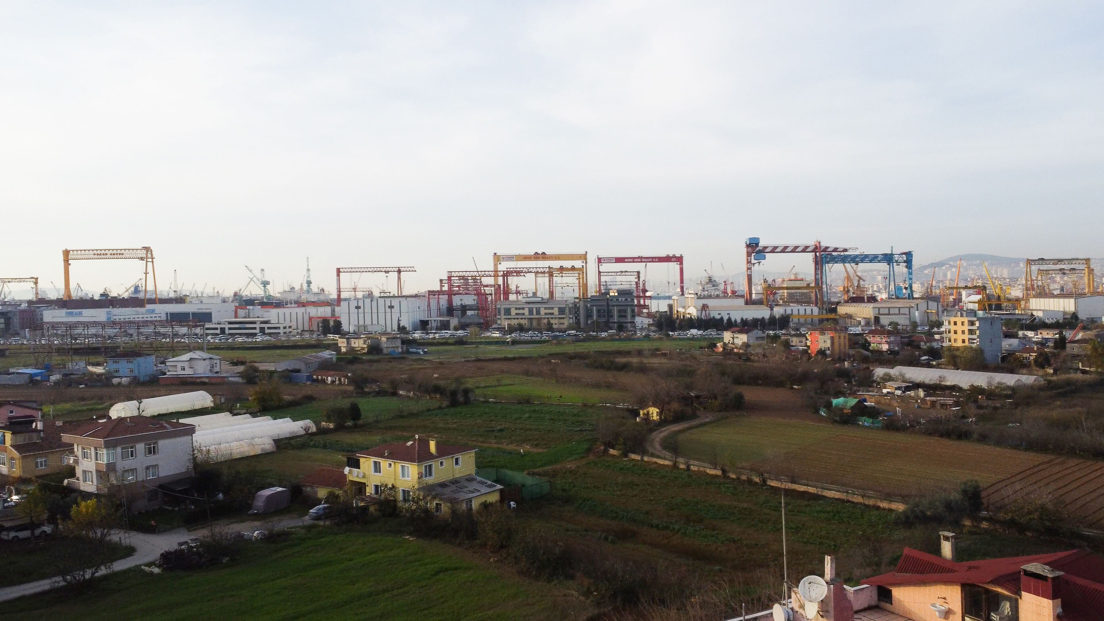 An industrial area with large cranes, warehouses, and residential buildings.