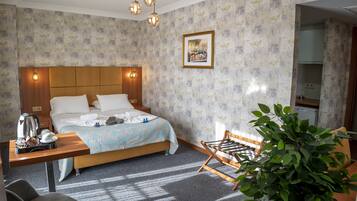 Habitación de hotel con cama, mesita de noche, silla y una planta en maceta.