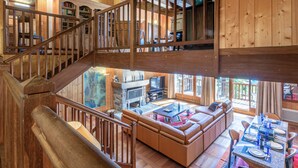 A spacious living area with a high wooden ceiling, a wooden staircase, a large leather sofa, and a dining table set for six. - Luxury chalet with sauna, fireplace and WiFi in Val-d'Isère (Val-d'Isère)