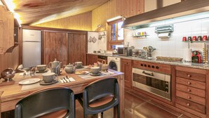 A modern kitchen with wooden cabinets, stainless steel appliances, and a dining area with chairs and a table set for a meal. - Luxury chalet with sauna, fireplace and WiFi in Val-d'Isère (Val-d'Isère)