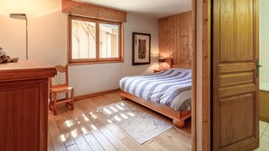 A bedroom with a wooden bed, a desk, a chair, a window, and a door. - Luxury chalet with sauna, fireplace and WiFi in Val-d'Isère (Val-d'Isère)