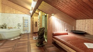 A wooden cabin interior with a wooden bench, a bathtub, and a stone sculpture. - Luxury chalet with sauna, fireplace and WiFi in Val-d'Isère (Val-d'Isère)