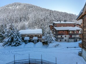 Un pueblo en la montaña cubierto de nieve, con edificios de madera y una pista de esquí.