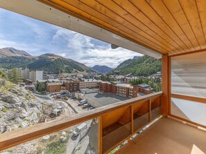 A balcony with a view of a mountainous town, buildings, and a construction site.