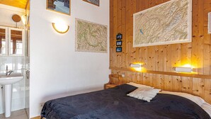 Ein Schlafzimmer mit Bett, Holz-Kopfteil, einer großen Karte und einem Badezimmer mit Waschbecken und Spiegel.