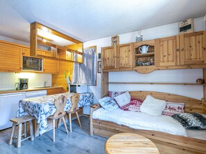 A compact living space with wooden furniture, a kitchenette, and a cozy seating area.