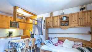 Un espace de vie compact, doté de meubles en bois, d’une kitchenette et d’un coin salon confortable.