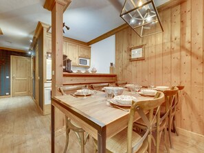 A wooden dining room with a table set for four, chairs, and a hanging light fixture.